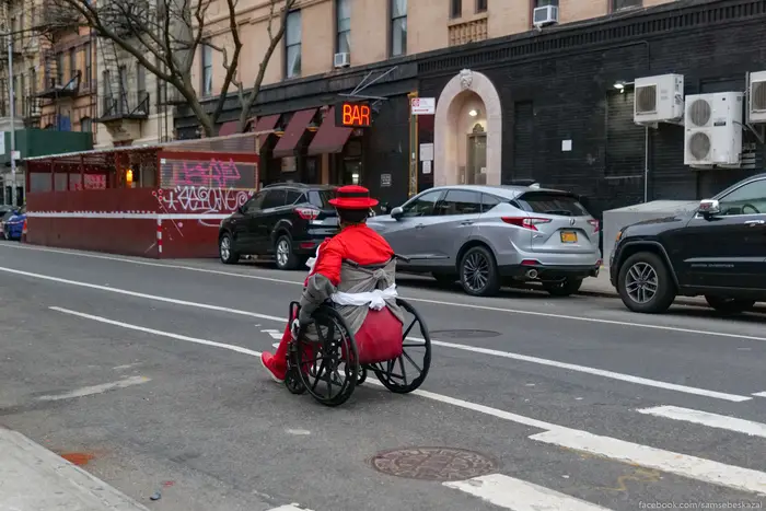 a person in a red outfit in a wheelchair passes a bar